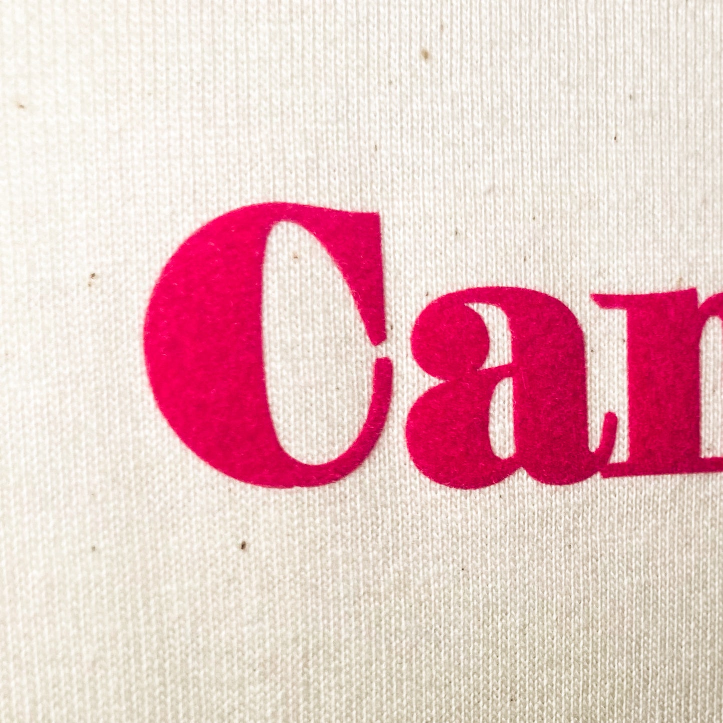 The Candle Carousel Candles To Action!®️ Charity. Pink Logo, Medium Weight T Shirt. Organic Cotton Fair Wear, Close Up Logo View