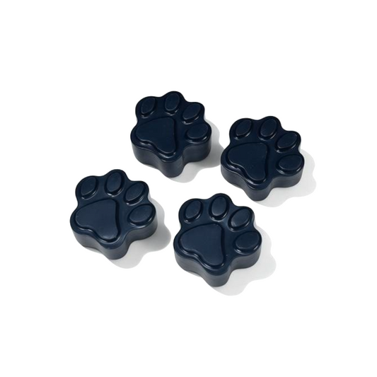 Four black paw-shaped wax melts on a white background